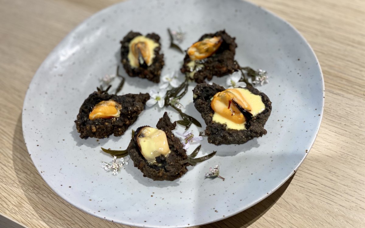 Musclos gratinats amb maionesa de safrà sobre xip d’arròs negre